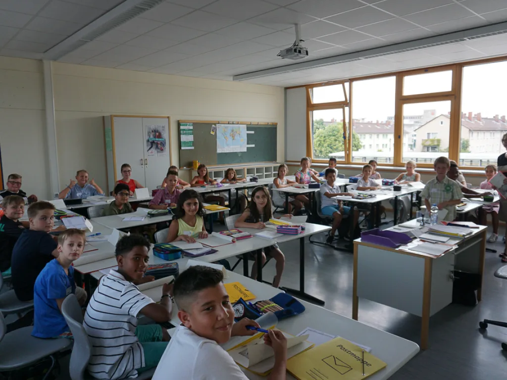Kinder sitzen in Reihen im Klassenraum.